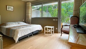 A bedroom with a bed, a desk with a computer, a chair, and a window with a view of greenery. - Beautiful Villa 8 guests - Pool Access in Mandelieu (Mandelieu-la-Napoule)