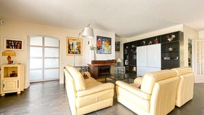 A living room with a sofa set, a glass coffee table, a fireplace, and a bookshelf. - Beautiful Villa 8 guests - Pool Access in Mandelieu (Mandelieu-la-Napoule)