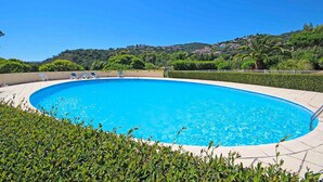 A clear blue swimming pool surrounded by well-maintained greenery and a hilly landscape in the background. - Beautiful Villa 8 guests - Pool Access in Mandelieu (Mandelieu-la-Napoule)