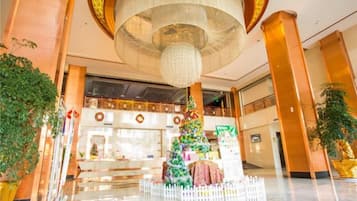 A lobby with a large chandelier, a Christmas tree, and a reception desk.
