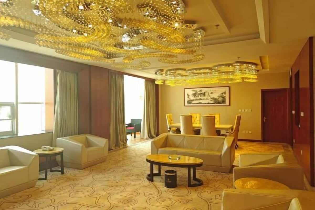 A hotel room with a large chandelier, a sofa set, a coffee table, and a painting on the wall.