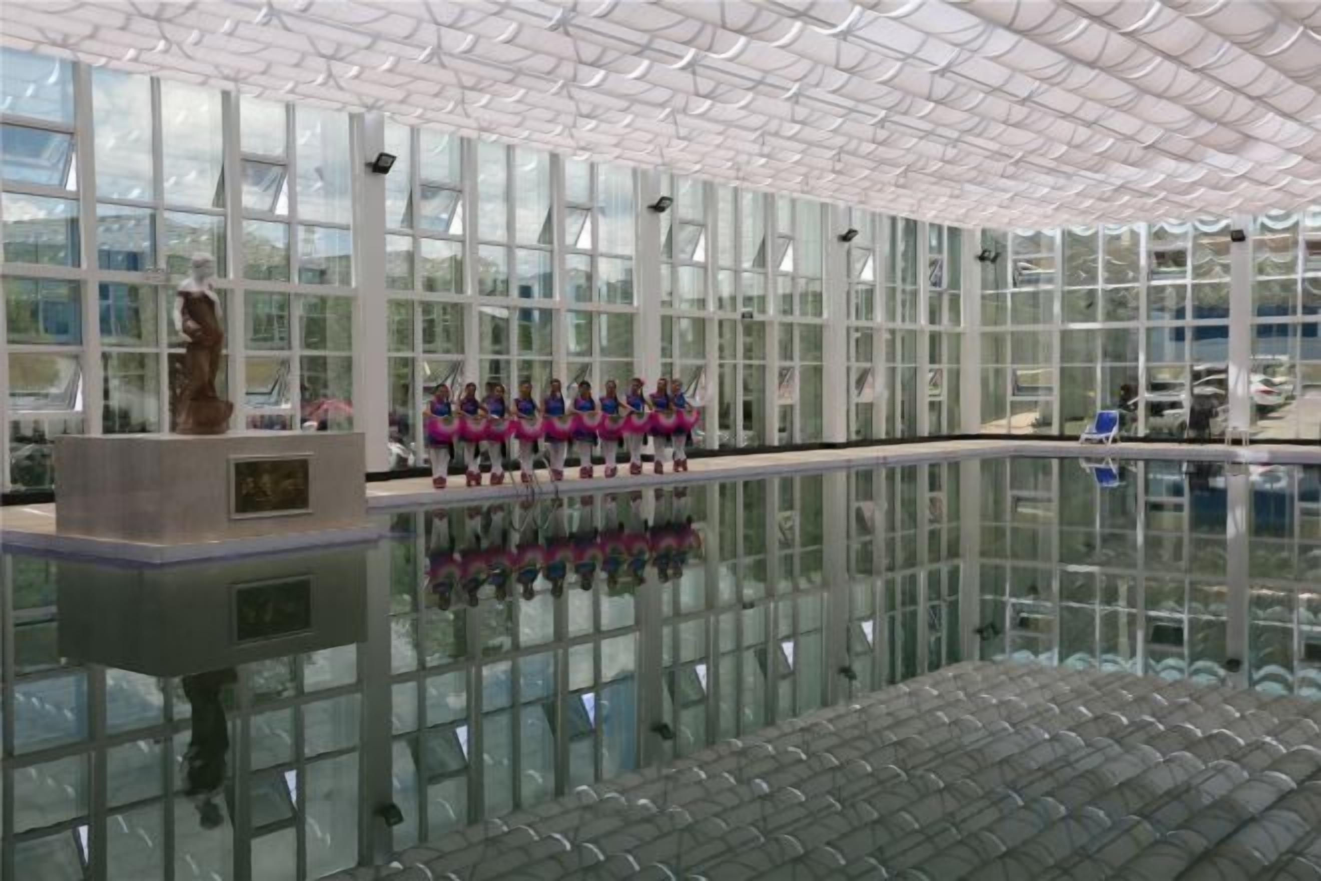 Una amplia piscina interior con paredes de vidrio transparente y techo de azulejos.