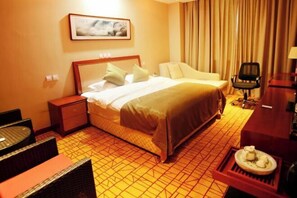 Ein Hotelzimmer mit einem Bett, einem Sessel, einem kleinen Tisch und einem Wandbild.