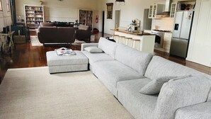 Un salon spacieux avec un grand canapé gris, une table basse et une bibliothèque remplie de livres.
