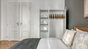 A bedroom with a bed, a wardrobe, and a closet with hanging clothes.