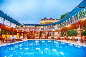 A pool area with a covered seating area and a building in the background. - GARDEN RUYA HOTEL (Fethiye)