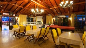 A dining area with wooden beams, yellow chairs, and white tables. - GARDEN RUYA HOTEL (Fethiye)