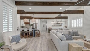 A spacious living area with a large sofa, a dining area with a kitchen in the background, and a wooden ceiling. - Stunning, Pet-Friendly,Beach Home Beside Dune Pool w/Extra Amenities Nearby (Port Aransas)