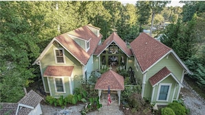A two-story house with a central porch and a small gazebo.