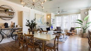 A spacious living room with a dining area, a large plant, and a map on the wall.