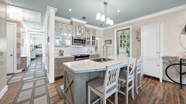A spacious kitchen with a central island, white cabinetry, and a bicycle in the corner.