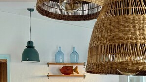Una cuina amb taula de fusta, penjallum de vímet i un bocal de vidre amb closques.