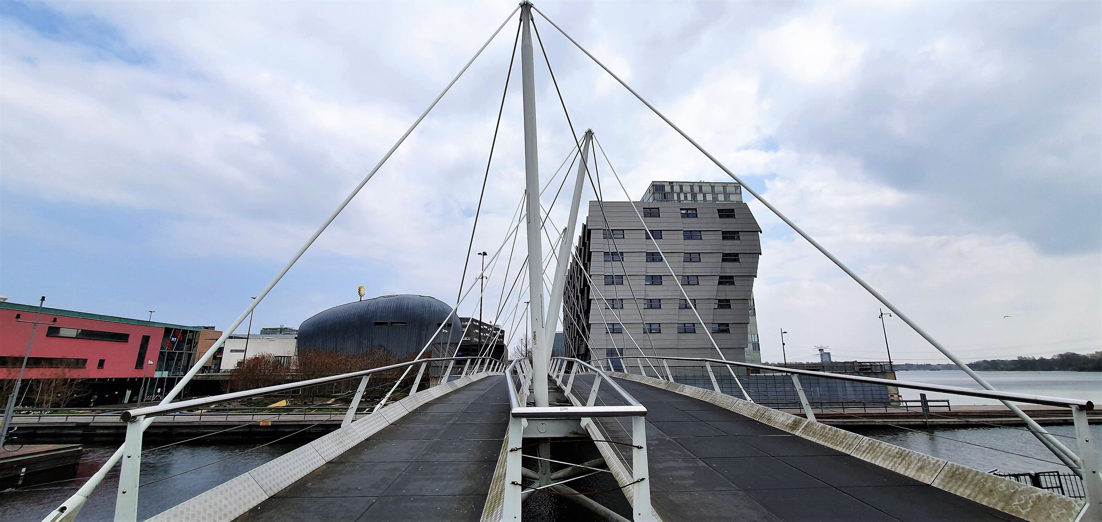 Een voetgangersbrug met een modern ontwerp, bestaande uit een metalen constructie en een looppad.