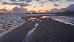 A beach with a curved shoreline, calm water, and a sunset sky. - Brand new apartment, next to Amsterdam and Floriade 2022, free parkingspace. (Almere)