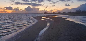 A beach with a curved shoreline, calm water, and a sunset sky. - Brand new apartment, next to Amsterdam and Floriade 2022, free parkingspace. (Almere)