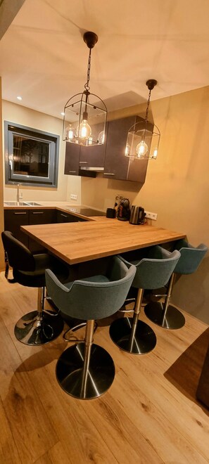 Een moderne keuken met een houten kookeiland, barkrukken, hanglampen en een raam met uitzicht op de omgeving.