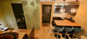 Een moderne keuken met een houten aanrecht, zwarte stoelen en een hanglamp.