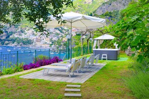 Una terrazza con posti a sedere all'aperto, una piscina e vista su una località costiera.