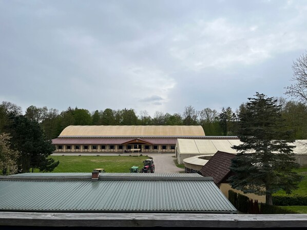 A large building with a flat roof, surrounded by trees and a grassy area.