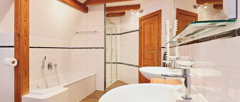 A modern bathroom with a bathtub, shower, and sink.