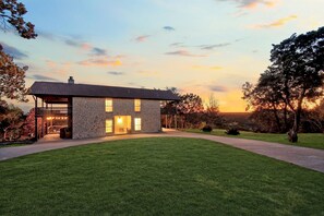 A modern house with a stone facade, large windows, and a covered porch.