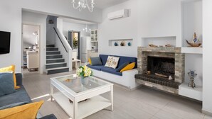 Una sala de estar moderna con chimenea, sofá, mesa de centro y una escalera que lleva a un nivel superior.
