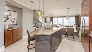 A modern kitchen with a central island, pendant lighting, and a view to the living area. - Contemporary Gulf Front Townhome Just Steps from the Water (Pensacola Beach)