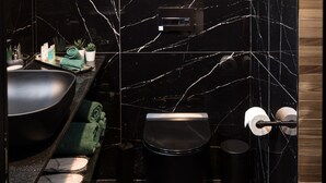 Un baño moderno con lavamanos, inodoro y cubo de basura de mármol negro.