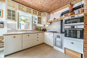 A kitchen with white cabinetry, a built-in oven, and a copper pipe on the wall.