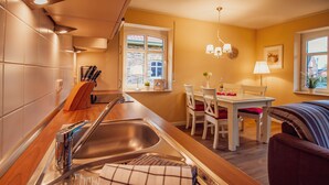 Une cuisine moderne dotée d’un évier en acier inoxydable, d’un plan de travail en bois et d’un coin repas avec une table et des chaises.