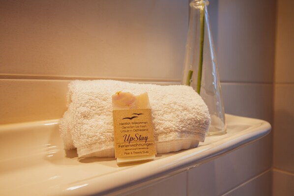 A white towel with a tag on a bathroom counter. - Int Hörn 1, Ground Floor (Krummhörn)