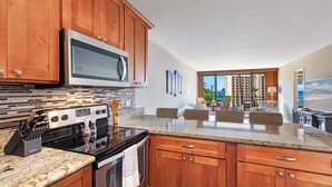 Una cocina moderna con armarios de madera, un microondas de acero inoxidable y una encimera de granito.