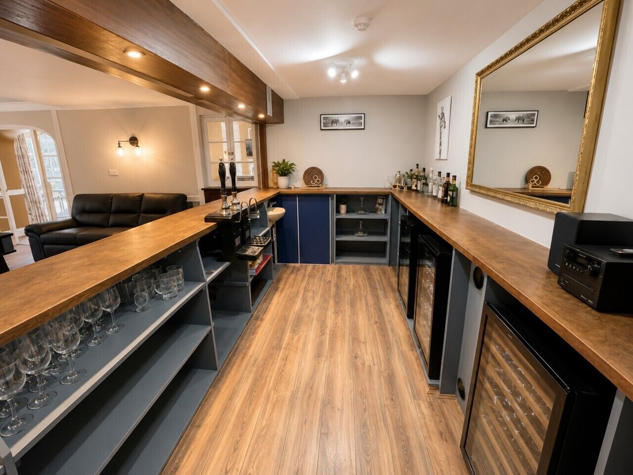 Une cuisine moderne avec un plan de travail en bois, des verres à vin et un grand miroir.
