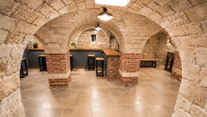 Interior de pedra amb sostres arquejats, un taulell central i zones d'ambientació.