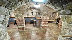 Una habitació de parets de pedra, amb un sostre alt, una banca al centre i una taula petita amb cadires.