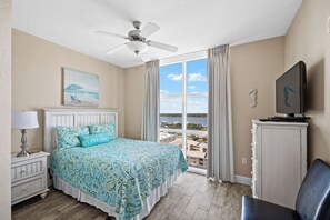 A bedroom with a bed, a nightstand, a TV on a cabinet, and a view of the water. - 3BR Gulf Front Condo | Sleeps 8 | Breathtaking Views (Gulf Shores)