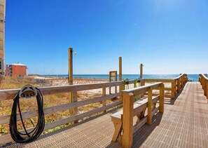 Une promenade en bois menant à une plage, avec un ciel dégagé.