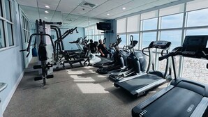 Une salle de sport équipée de tapis de course, de vélos elliptiques et d'appareils de musculation.