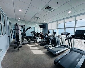 Une salle de sport équipée de tapis de course, de vélos elliptiques et d'appareils de musculation.