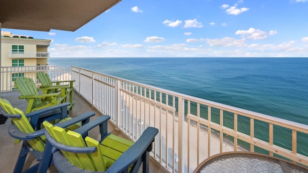 Un balcon avec des chaises vertes et une vue sur l’océan.