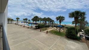A resort pool area with a view of the beach, palm trees, and a clear sky.