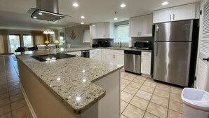A modern kitchen with granite countertops, stainless steel appliances, and white cabinetry.
