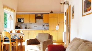 A compact living space with a kitchen, dining area, and a sofa. - Quietly situated apartment for max. 4 persons, balcony, garden, WLAN, washing machine (Prerow)
