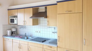 A kitchen with light wood cabinets, a stainless steel sink, a microwave, and a coffee maker. - Quietly situated apartment for max. 4 persons, balcony, garden, WLAN, washing machine (Prerow)