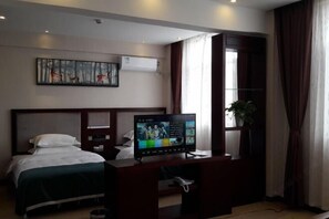 Habitación de hotel con cama, escritorio con computadora, televisión y un cuadro en la pared.