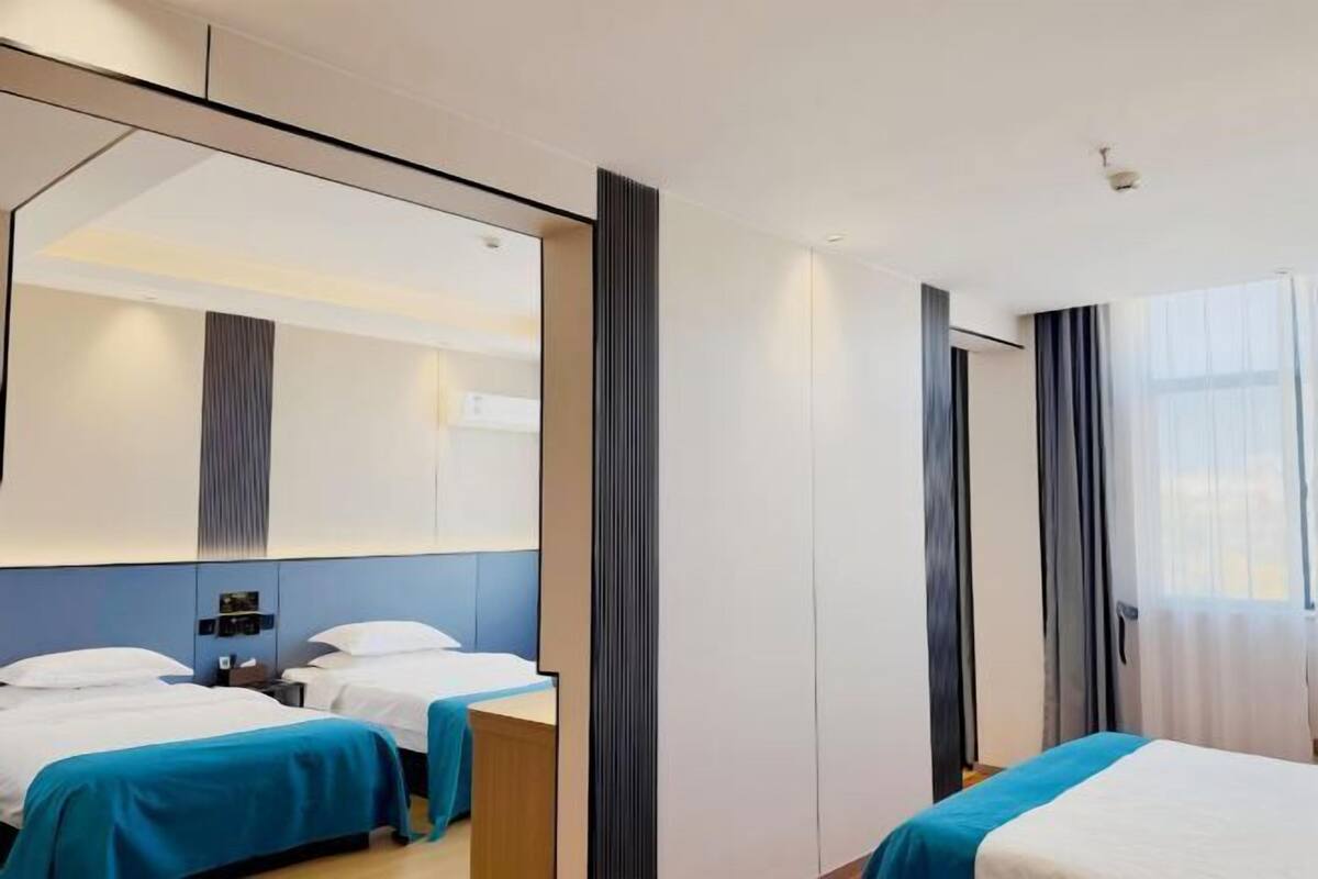 Une chambre d’hôtel avec deux lits, un grand miroir et une armoire.