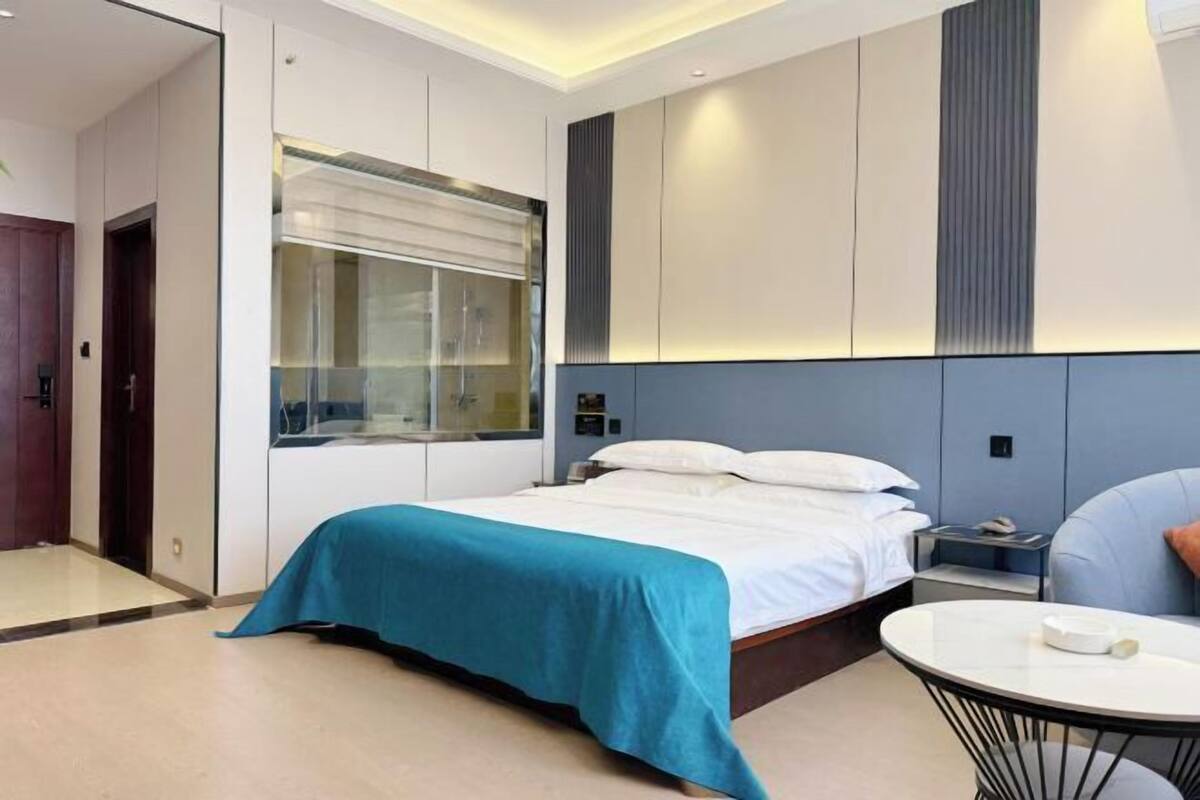 Une chambre d’hôtel moderne avec un lit, une table de chevet et une petite table ronde.
