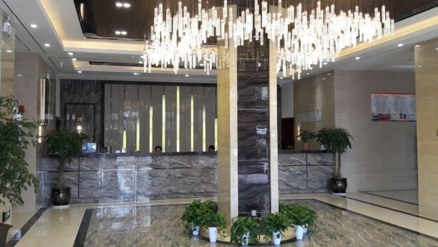 Una hall con una reception in marmo, una colonna centrale e lampade a sospensione.