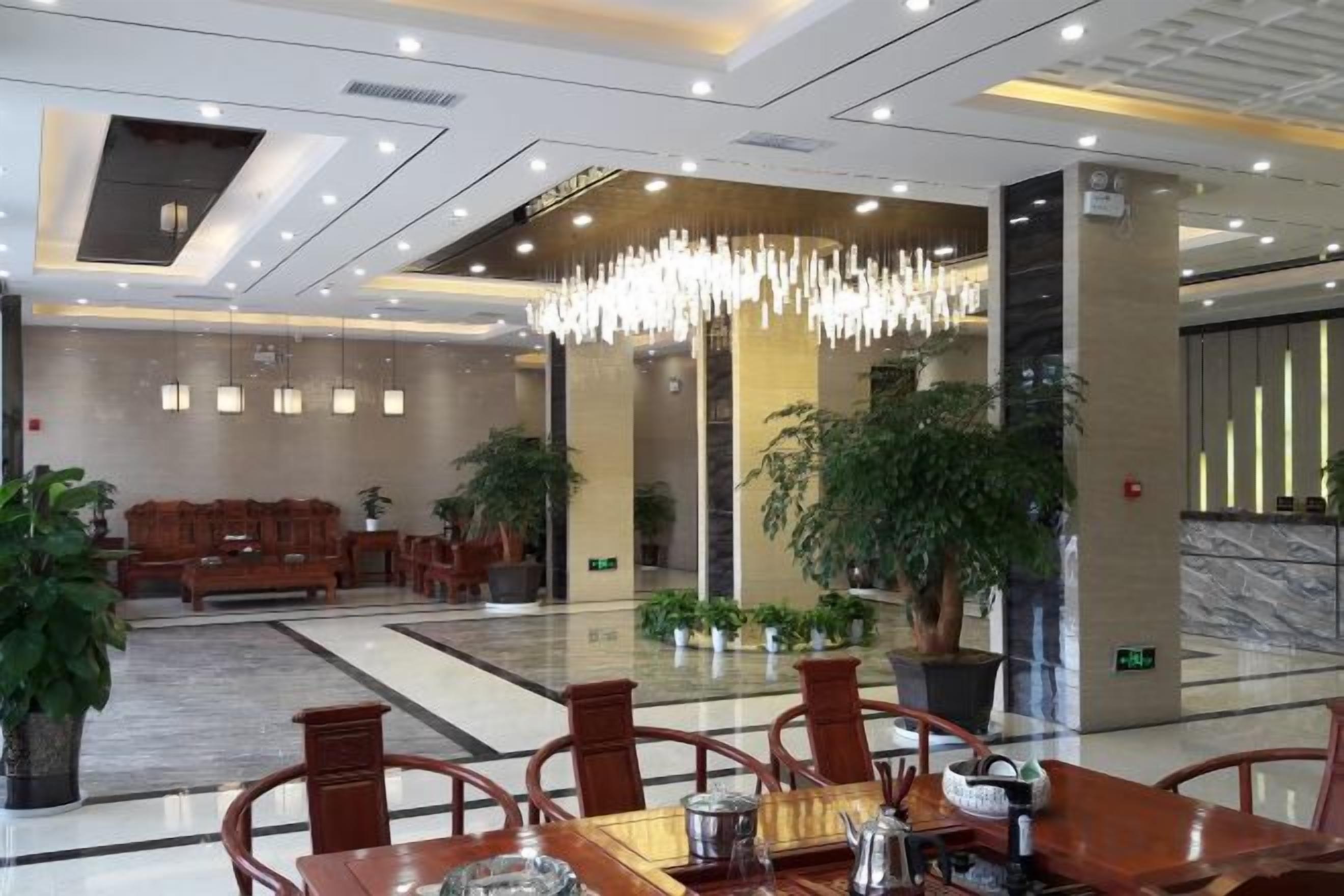 A hotel lobby with a reception desk, seating area, and a chandelier.