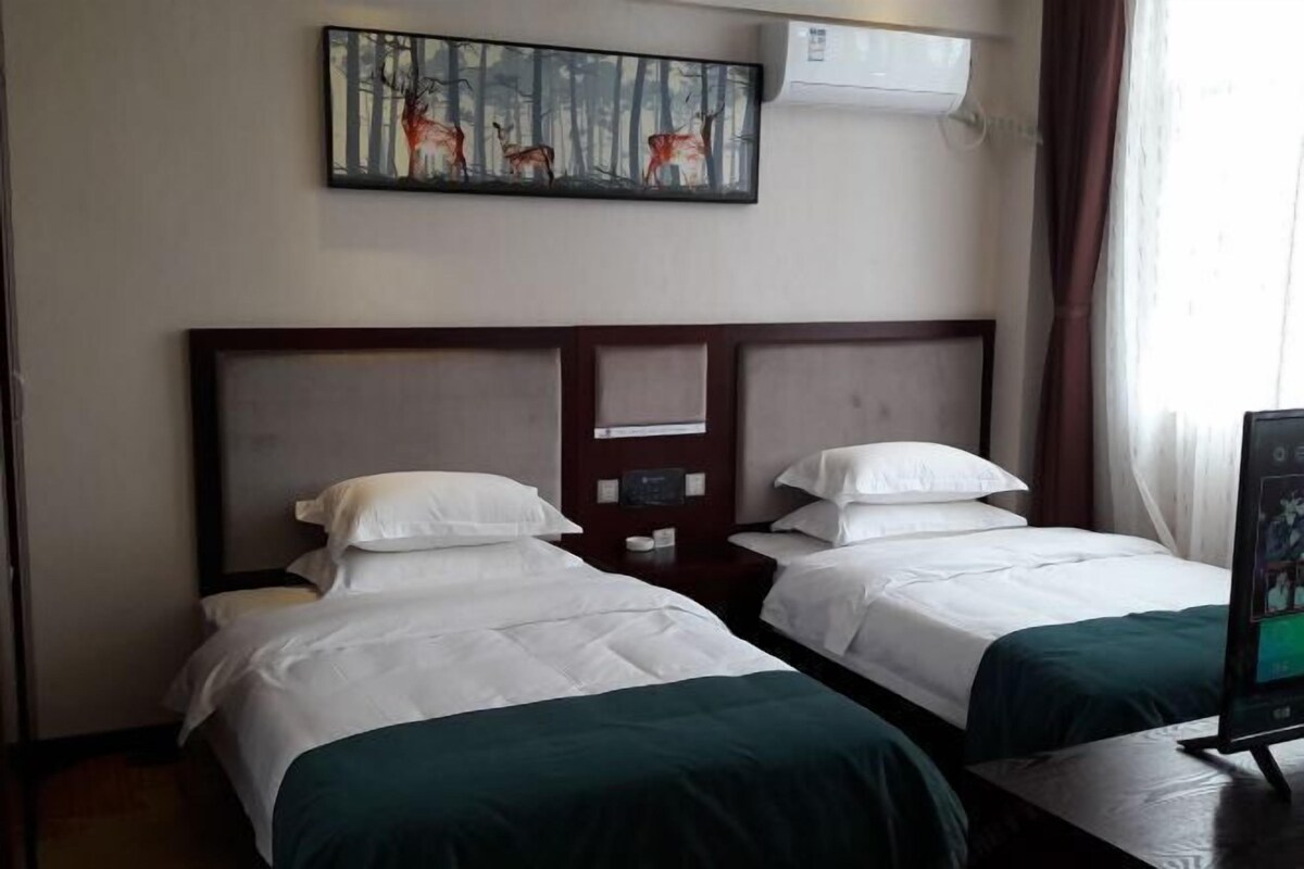 Habitación de hotel con dos camas, un cuadro de ciervos en la pared y un televisor sobre una mesita.